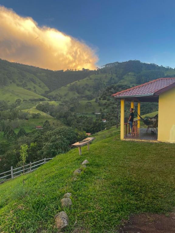 a person standing on the porch of a house on a hill at Chalé Pico da Lua in Gonçalves