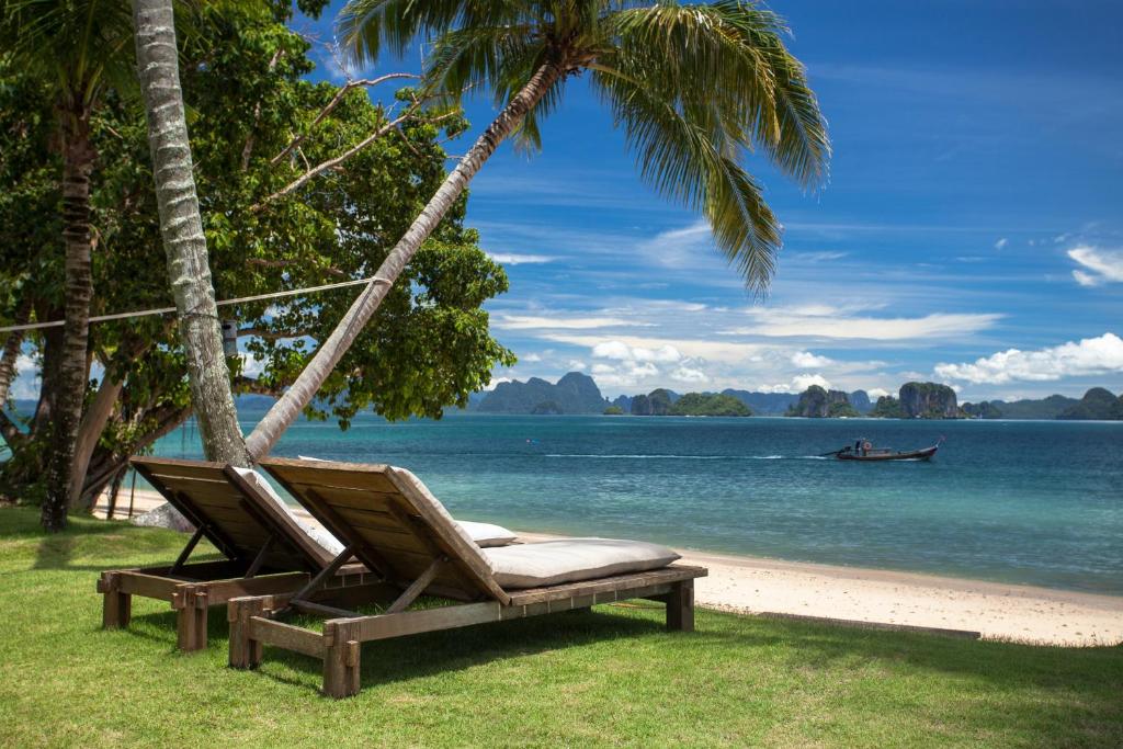 eine Hängematte am Strand mit einem Boot im Wasser in der Unterkunft Koyao Island Resort in Ko Yao Noi