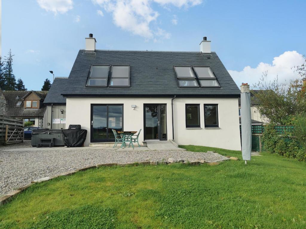 una casa bianca con tavolo e sedie nel cortile di Berg Cottage a Ballindalloch