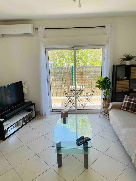 un salon avec un canapé et une table basse en verre dans l'établissement Apartment 2 steps from Bergerie Beach!, à Hyères