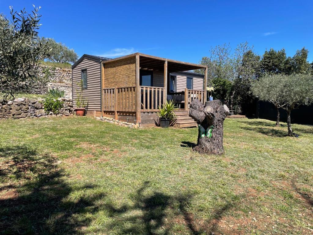 a house with a tree stump in the yard at Mobil-home en pleine nature à 3 mins du Lac du Salagou avec vue panoramique in Lacoste