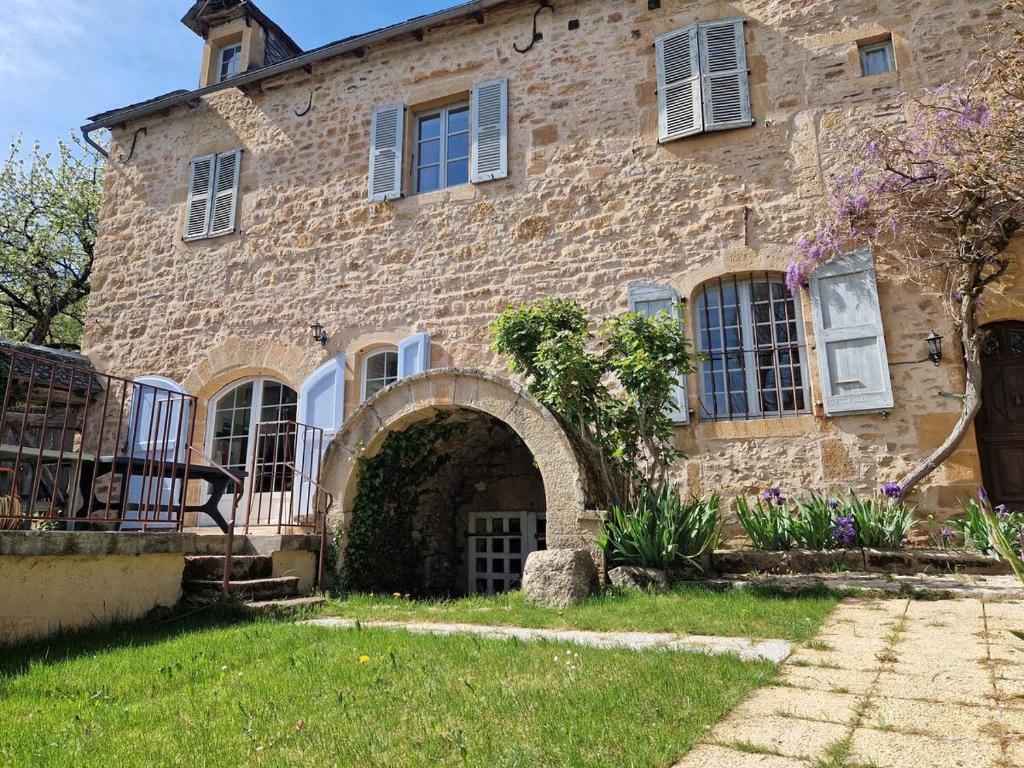 - un bâtiment en pierre avec une arche devant dans l'établissement Gite de Montrepos - Ancien Presbytère XVIIe siècle, à Estaing