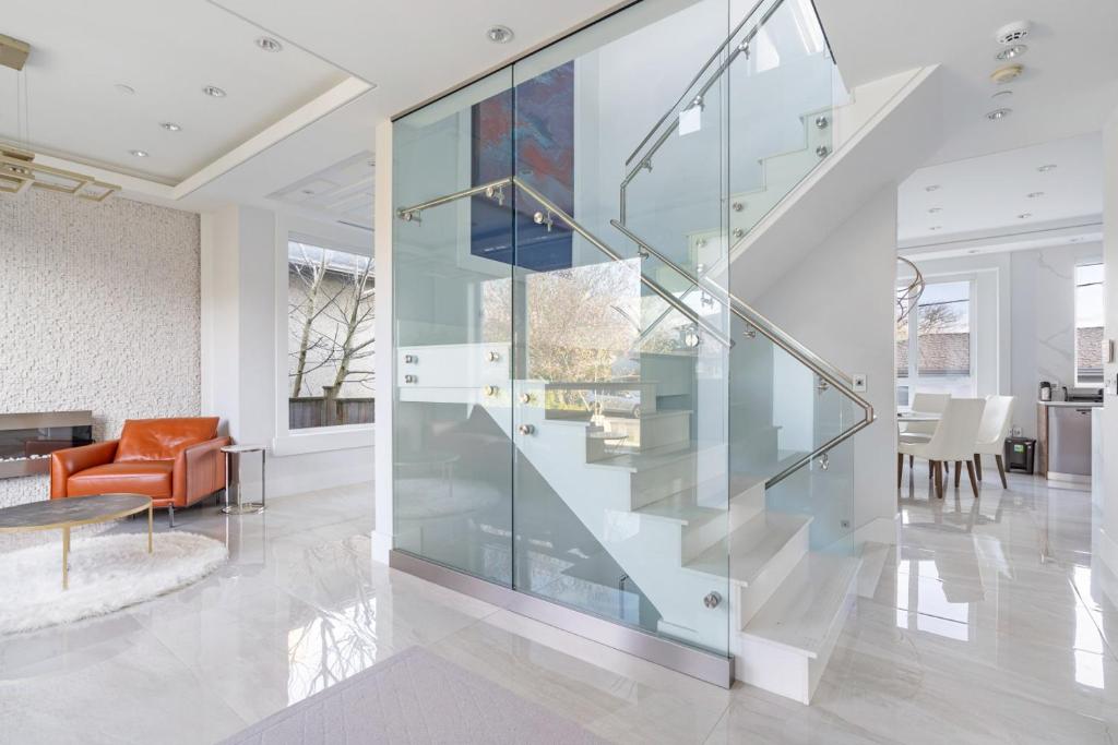 a glass staircase in a living room with an orange chair at Centrally Located Luxury Home with Views and Cinema in Vancouver