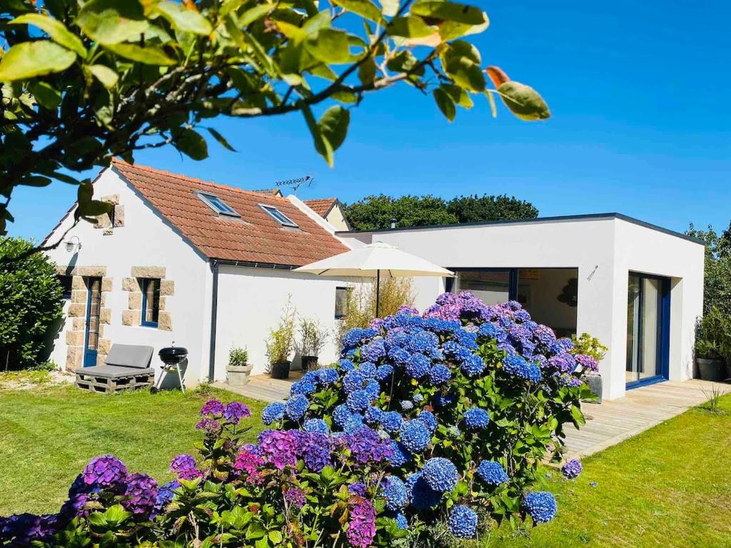 une maison blanche avec des fleurs violettes dans la cour dans l'établissement Le havre de paix de la Côte de granit rose, à Pleumeur-Bodou