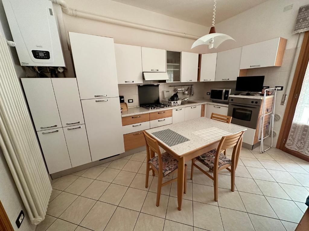 a kitchen with white cabinets and a table and chairs at Leopardi 81 - 400 mt dall' AUTODROMO F1 in Imola