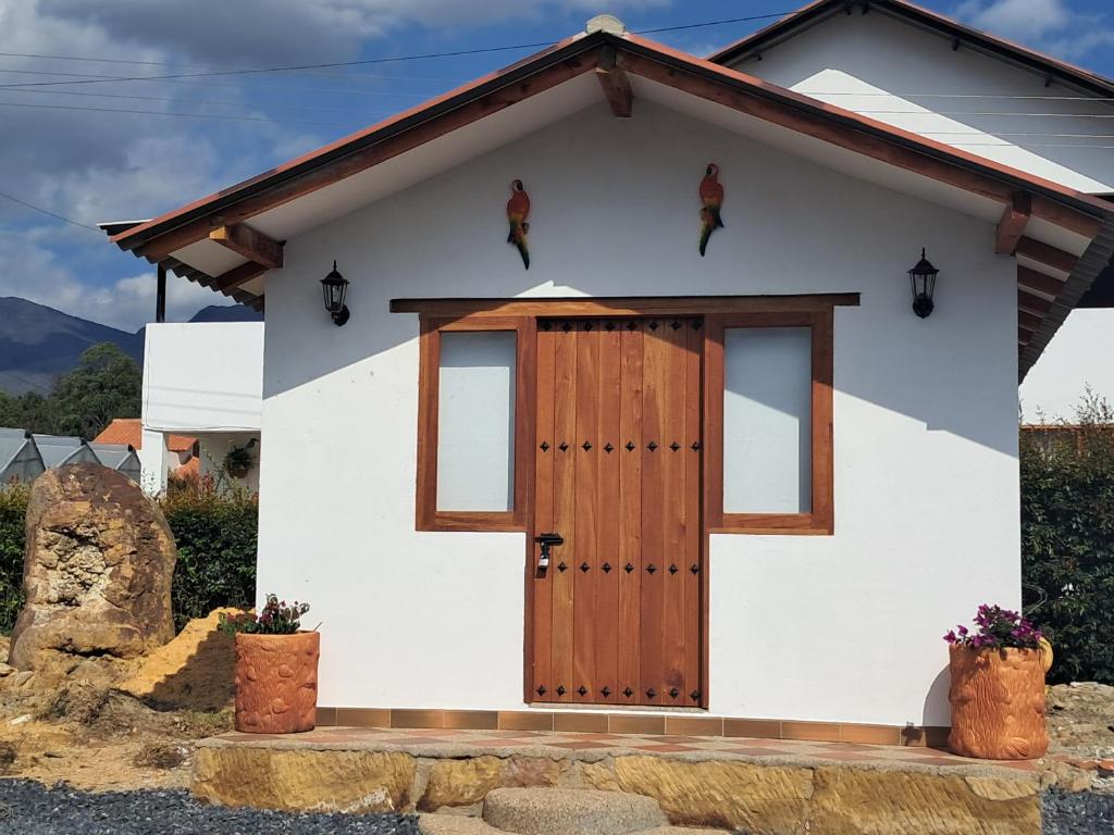 Casa blanca pequeña con puerta de madera en Cabaña Deluxe en Villa de Leyva, VillaClarita, en Villa de Leyva