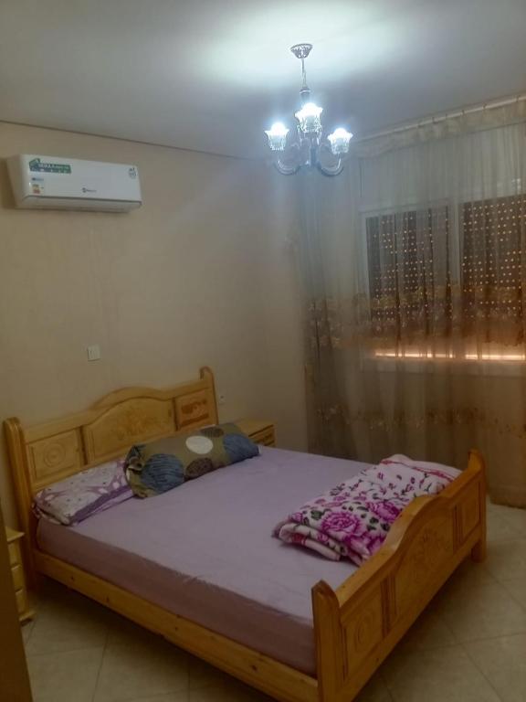 a bedroom with a wooden bed with purple sheets at aggens immobiler nador in Nador