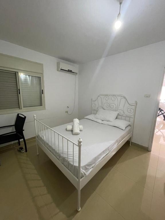 - un lit blanc dans une chambre blanche avec une chaise dans l'établissement חופשה מושלמת על הכנרת, à Tel Aviv