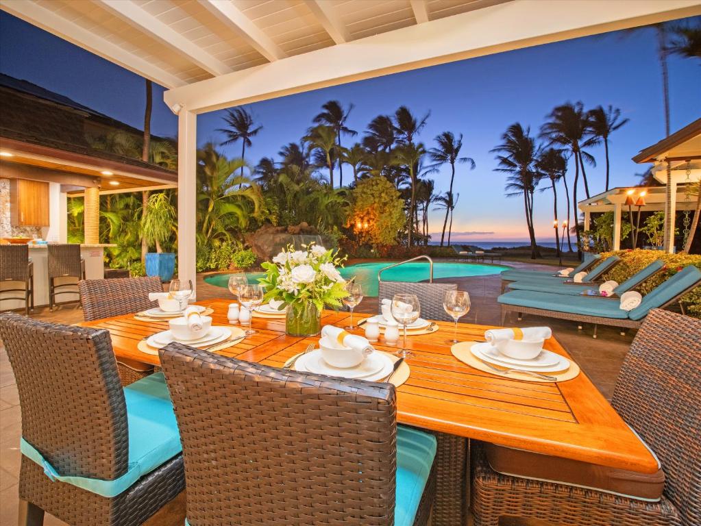 einen Essbereich im Freien mit einem Holztisch und Stühlen in der Unterkunft Remodeled Beachfront Estate, Magnificent Mango Surf in Kihei