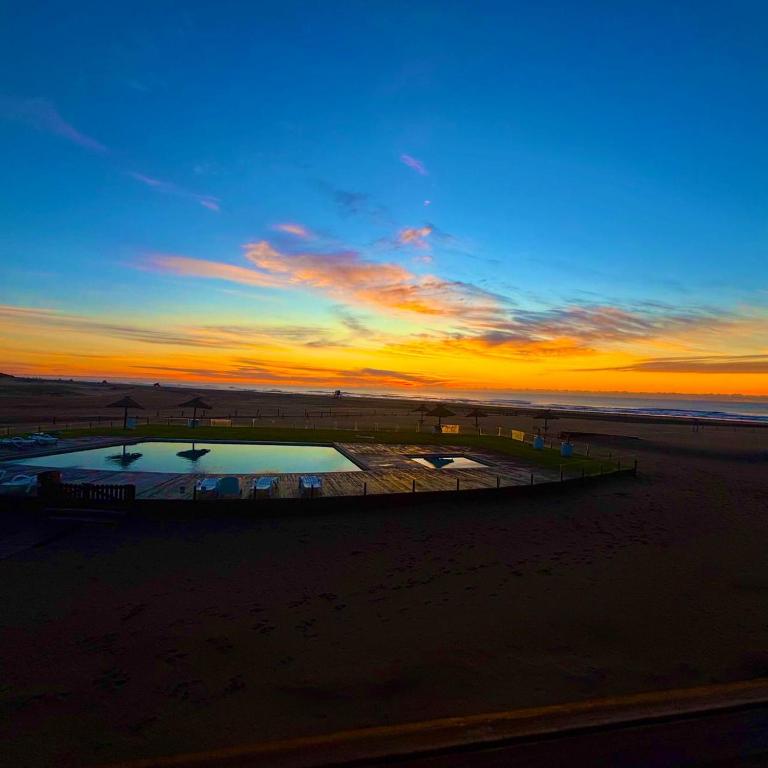 a sunset at the beach with a pool in the sand at Chacras del Mar 4x4 in Mar Azul