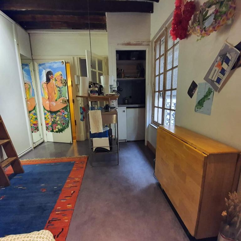 un salon avec une table et une cuisine dans l'établissement charmant studio à Marais Paris centre, à Paris