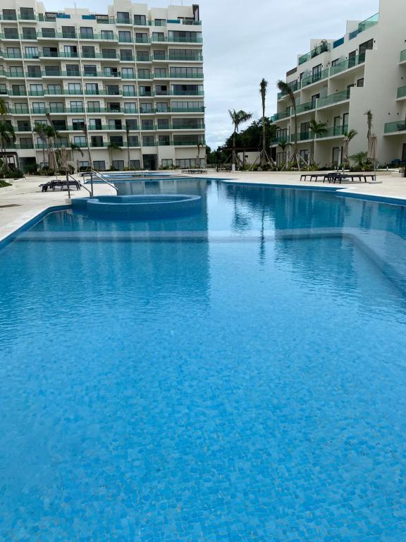 a large pool of blue water in front of buildings at Depa boutique nuevo de 2 recámaras - diseño, confort y excelente ubicación con alberca in Playa del Carmen