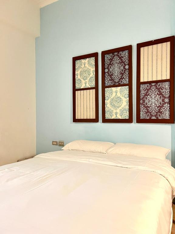 a white bed in a room with three windows at Hour Roots in Tainan