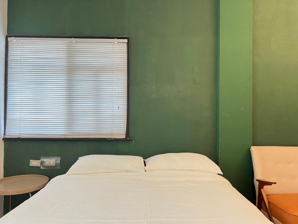 a bed in a green room with a window at Hour Roots in Tainan