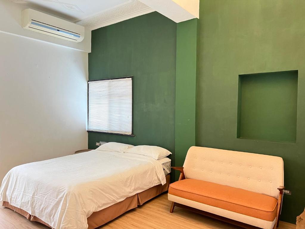 a bedroom with green walls and a bed and a chair at Hour Roots in Tainan