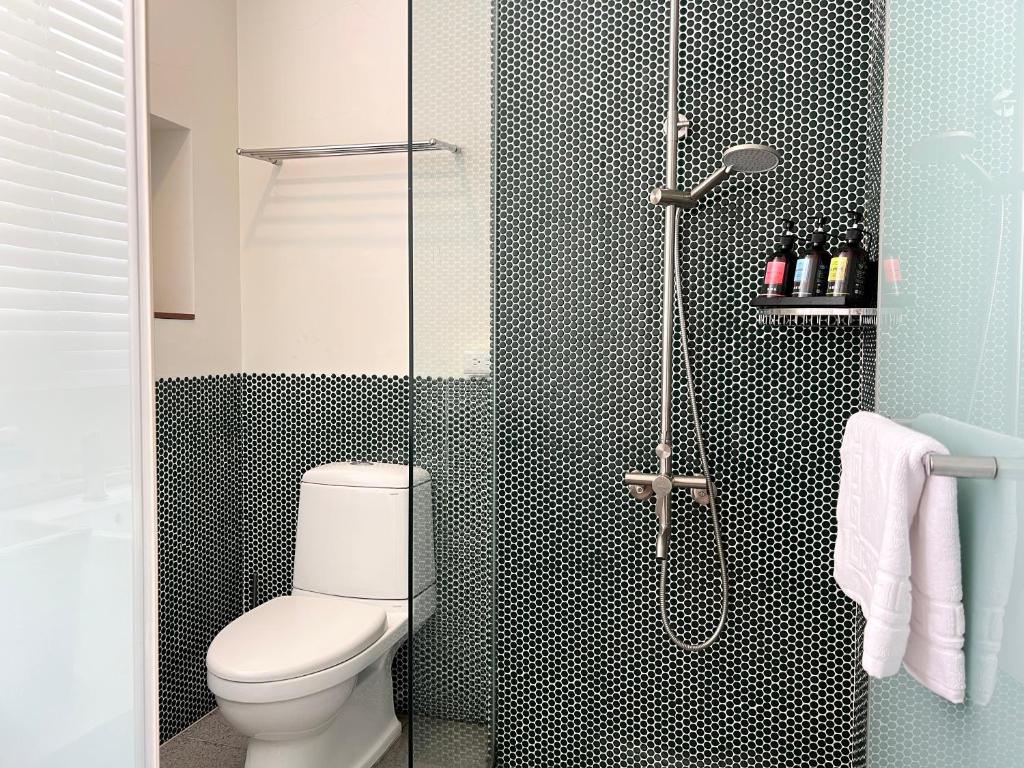a bathroom with a toilet and a glass shower at Hour Roots in Tainan