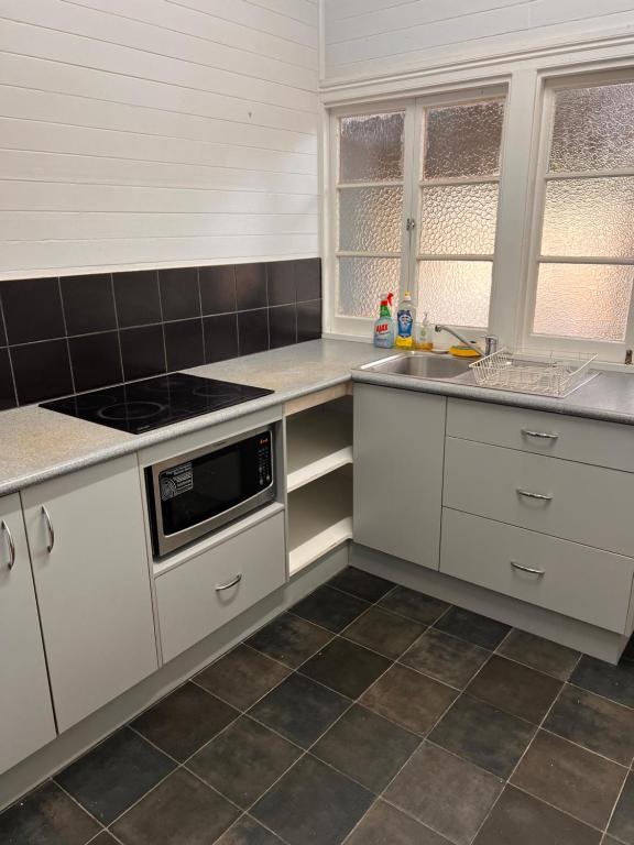 a kitchen with white cabinets and a stove at Ryan's Rest Boutique Accommodation in Cairns