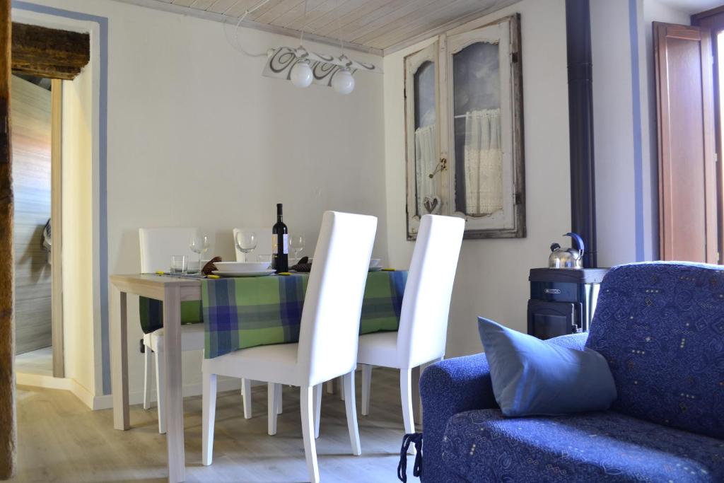 einem Esstisch mit weißen Stühlen und einem blauen Sofa in der Unterkunft Home Love Home in Casasco Intelvi