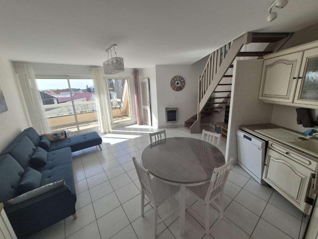 un salon avec une table et un canapé bleu dans l'établissement Duplex T3 lumineux avec garage à Berck-Plage - FR-1-674-50, à Berck-sur-Mer