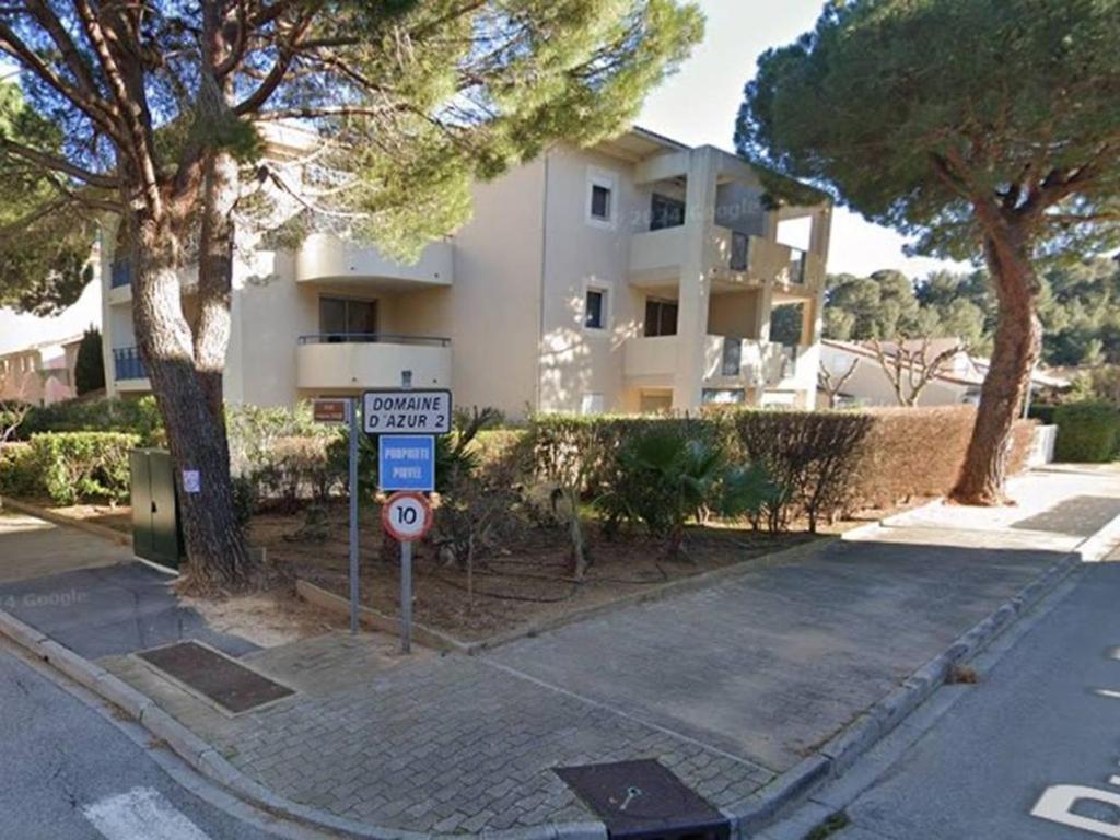 un panneau de rue devant un bâtiment blanc dans l'établissement Appartement T2 avec terrasse, piscine et parking, proche plage - FR-1-803-93, au Lavandou