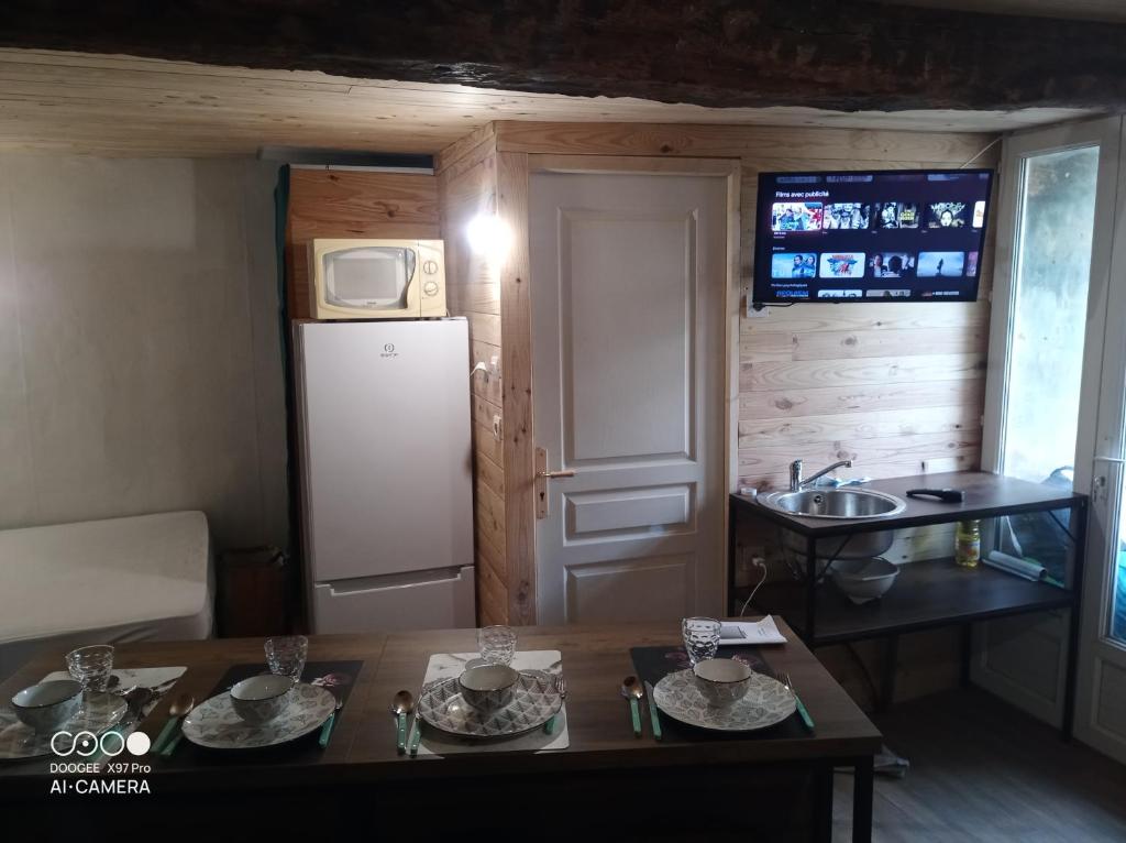 a small kitchen with a refrigerator and a table at Petit village authentique 2 in Mauléon-Barousse