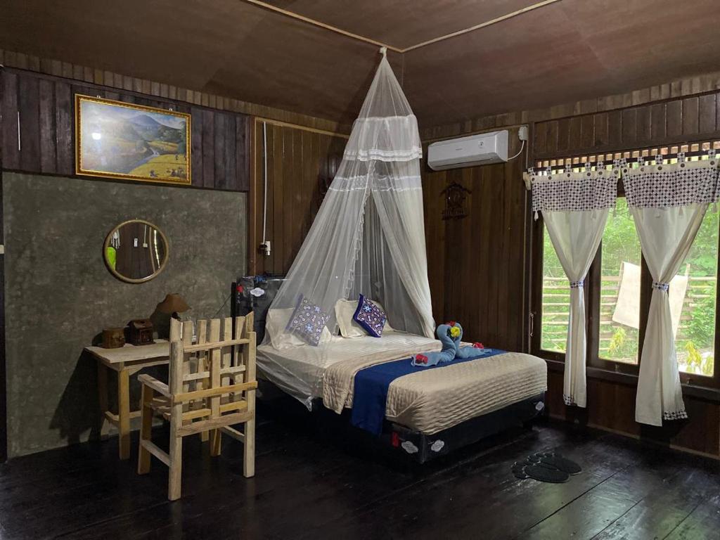 a bedroom with a bed with a mosquito net at Loh jinawi Guest House Bunaken in Bunaken