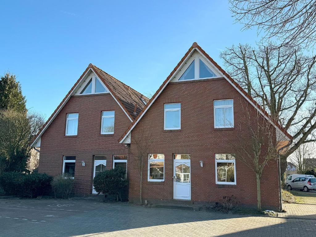 a large red brick house with white windows at Ferienwohnungen Hinrichs in Carolinensiel