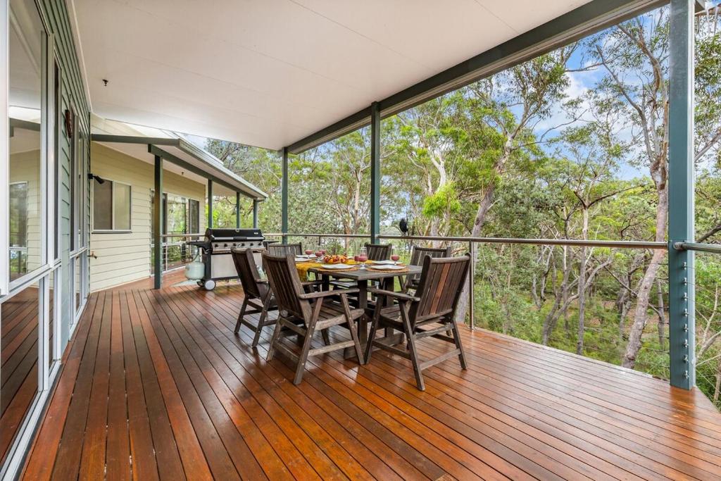 a dining room with a table and chairs on a deck at Triple B - Beach Bush Birds in Dunbogan
