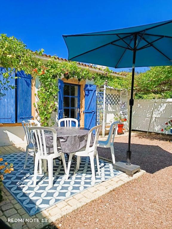 une table et des chaises avec un parapluie bleu dans l'établissement Le Jardin des Muses, à Jard-sur-Mer