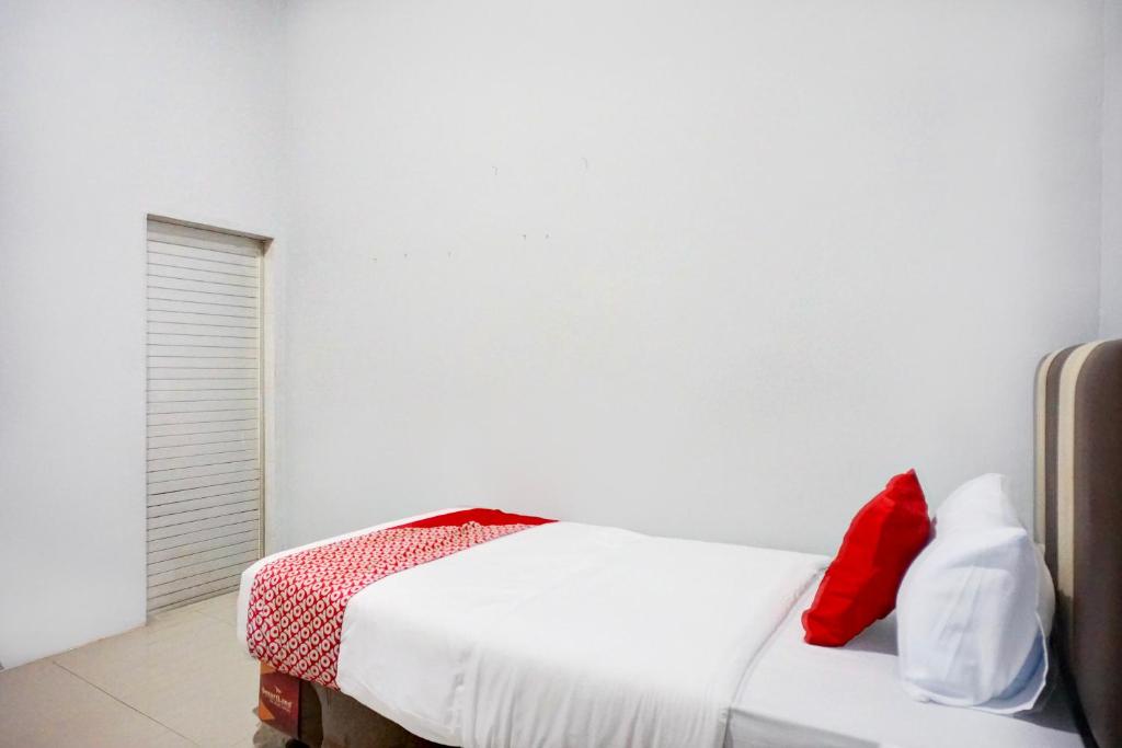 Pulauberayan DadapDancenter Pancing Near Universitas Negeri Medan UNIMED Formerly Nadira Homestay的卧室配有白色的床和红色枕头