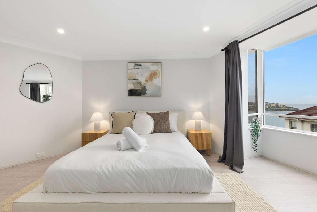 a white bedroom with a large bed and a large window at Amazing Ocean View Studio at Bondi Beach in Sydney
