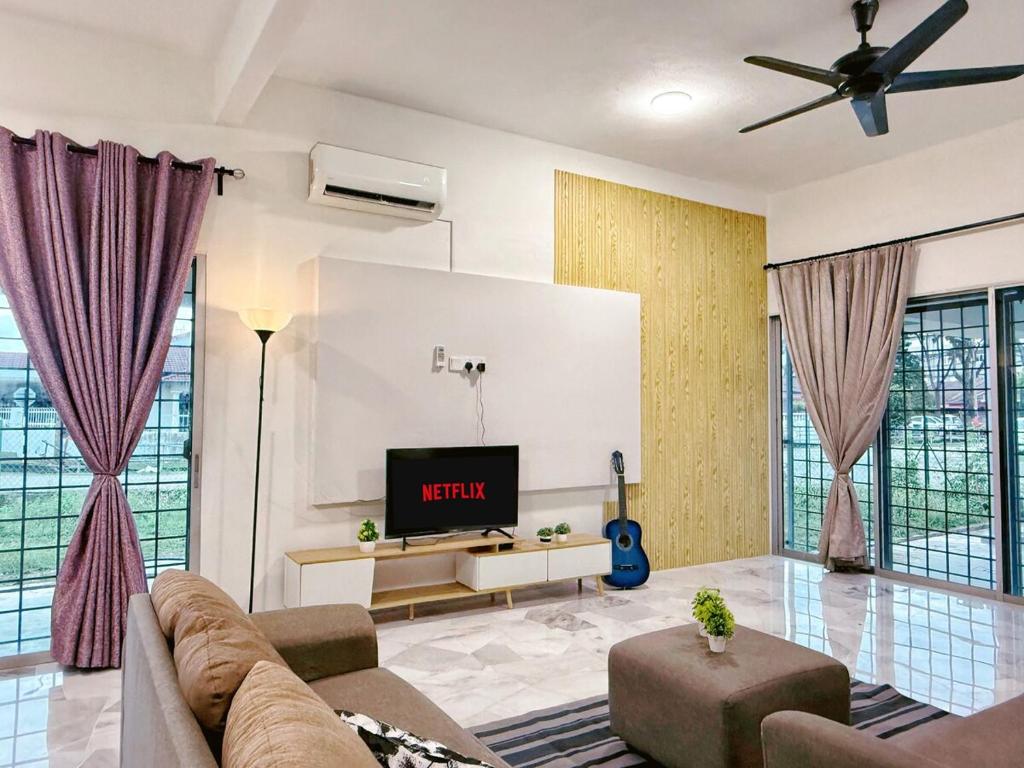 Una sala de estar con un sofá y un televisor. en Outdoor BBQ Air Putih 4R3B Homestay, en Kuantan