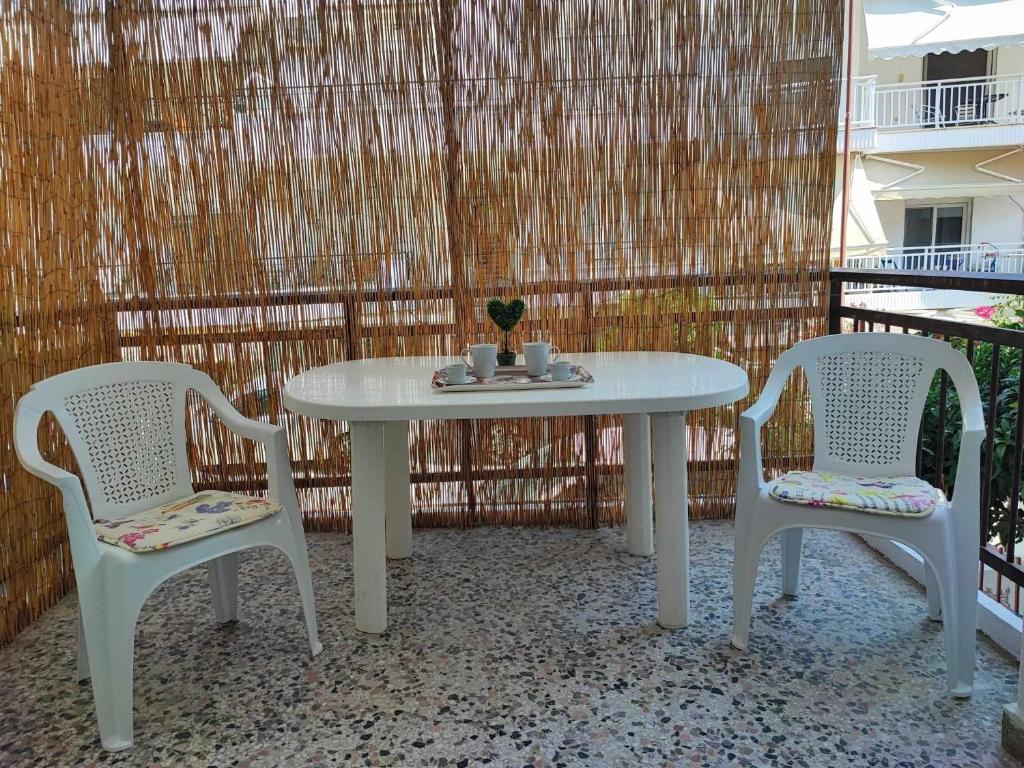 - une table blanche et 2 chaises sur la terrasse dans l'établissement Lidia Apartments Nea Peramos 1, à Néa Péramos