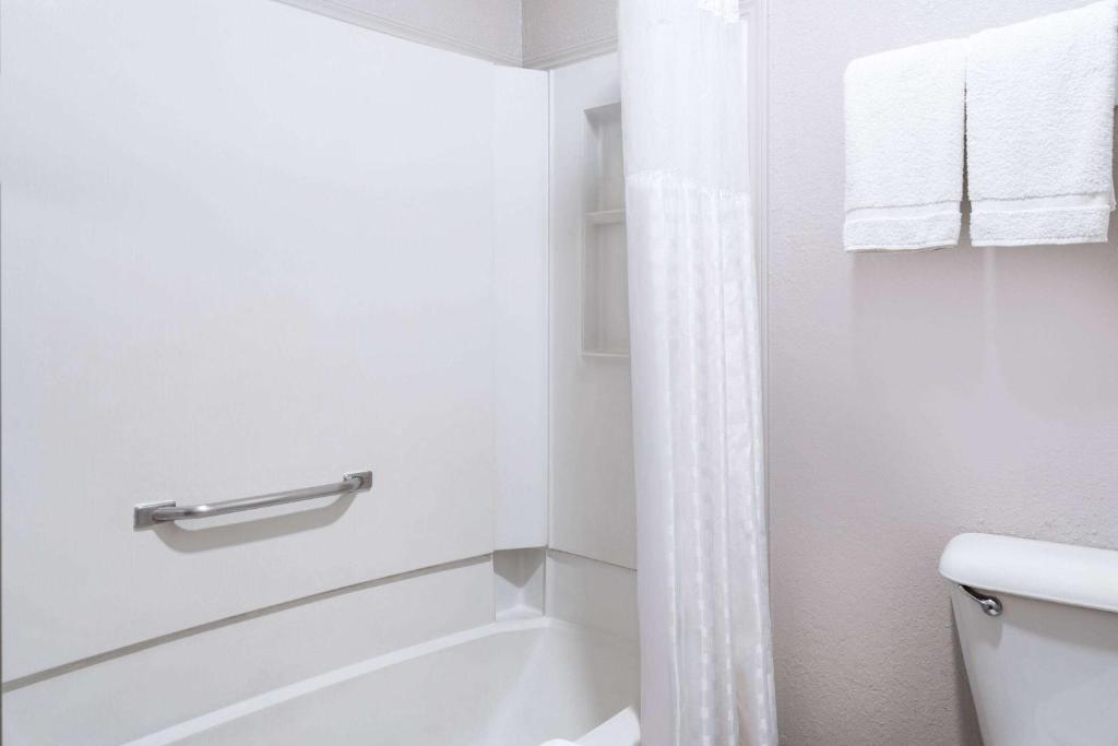 a white bathroom with a tub and a toilet at Days Inn by Wyndham Ardmore in Ardmore