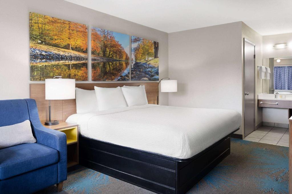 a hotel room with a bed and a blue chair at Days Inn by Wyndham Ardmore in Ardmore