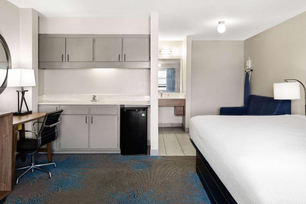 a bedroom with a bed and a desk and a kitchen at Days Inn by Wyndham Ardmore in Ardmore