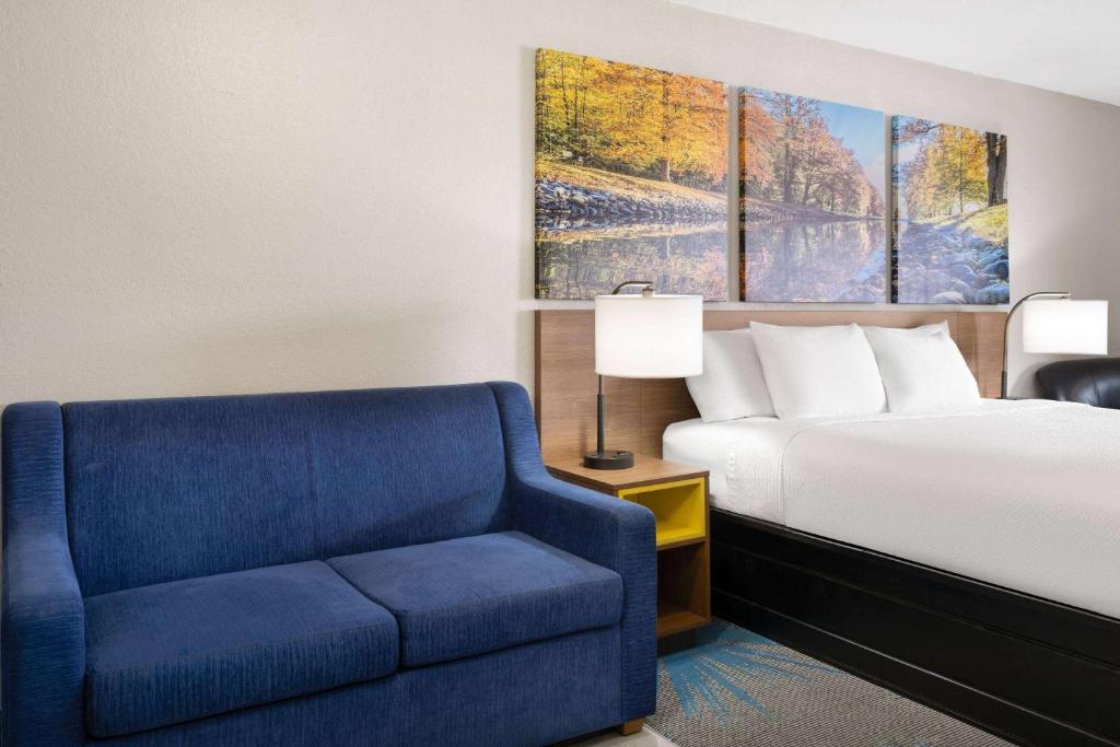 a bedroom with a bed and a blue chair at Days Inn by Wyndham Ardmore in Ardmore