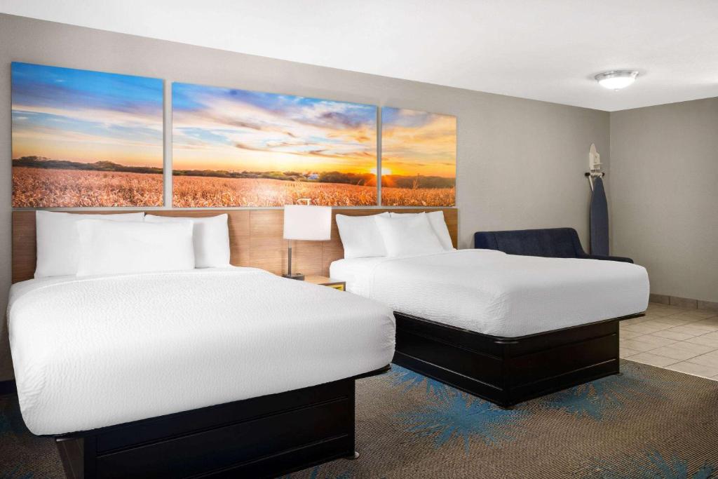 two beds in a hotel room with a painting on the wall at Days Inn by Wyndham Ardmore in Ardmore