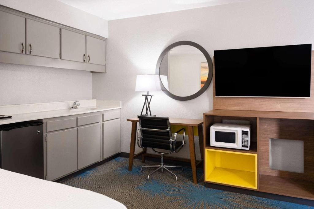 a room with a desk with a microwave and a tv at Days Inn by Wyndham Ardmore in Ardmore