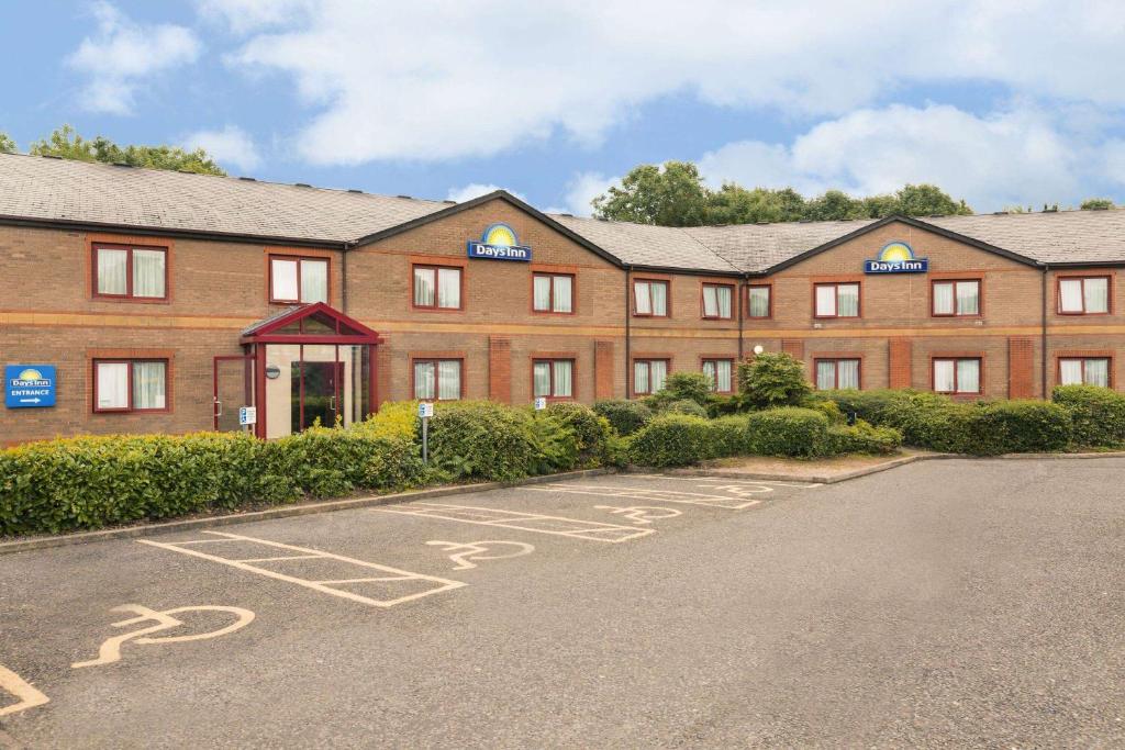 a large red brick building with a parking lot at Days Inn Magor in Magor