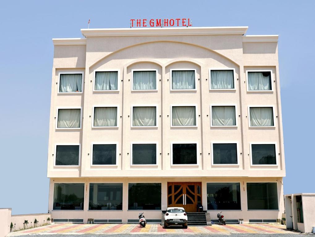 KhātuThe GM Hotel的一栋建筑前停着一辆车