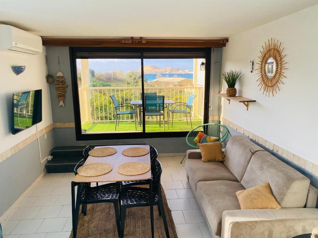 un salon avec un canapé et une table dans l'établissement La Petra Marinella - Appt climatisé avec piscine, à LʼÎle-Rousse