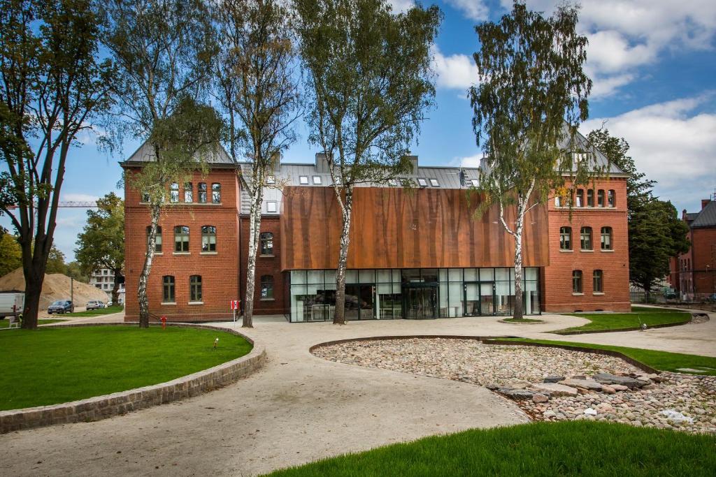 un bâtiment en briques rouges avec des arbres devant lui dans l'établissement Studio Kampus Garnizon, à Gdańsk