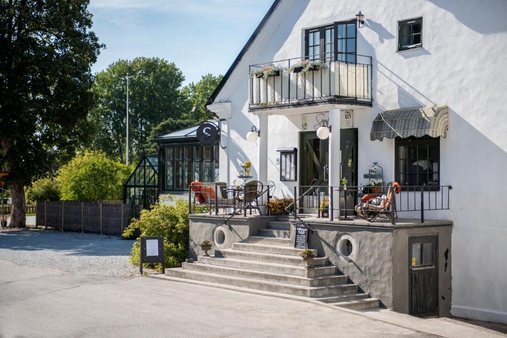 a white house with stairs and a balcony at Smakrike Krog & Logi in Ljugarn