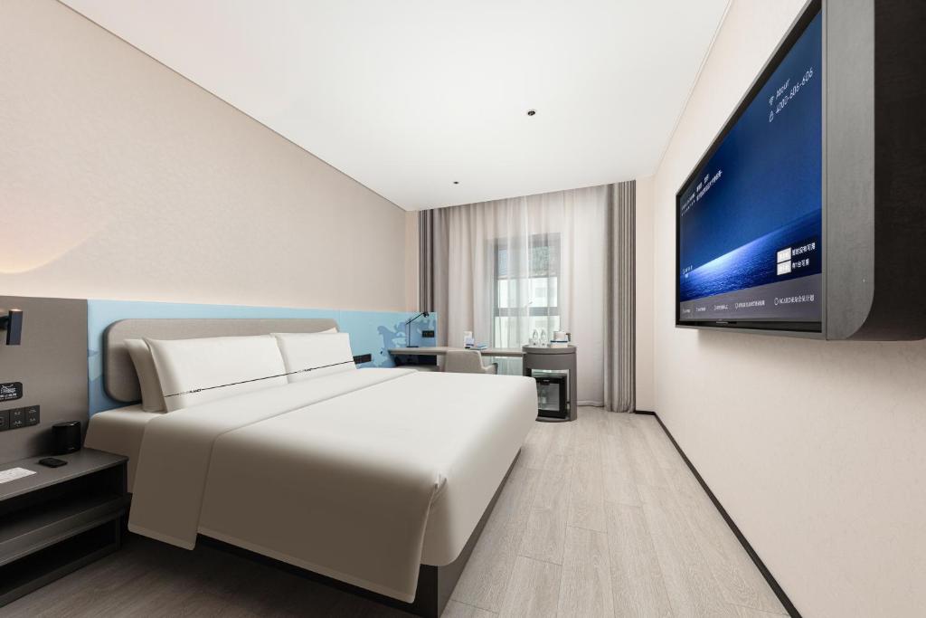 a bedroom with a white bed and a flat screen tv at Atour Light Hotel Wuhan Optics Valley Square Subway Station in Wuhan