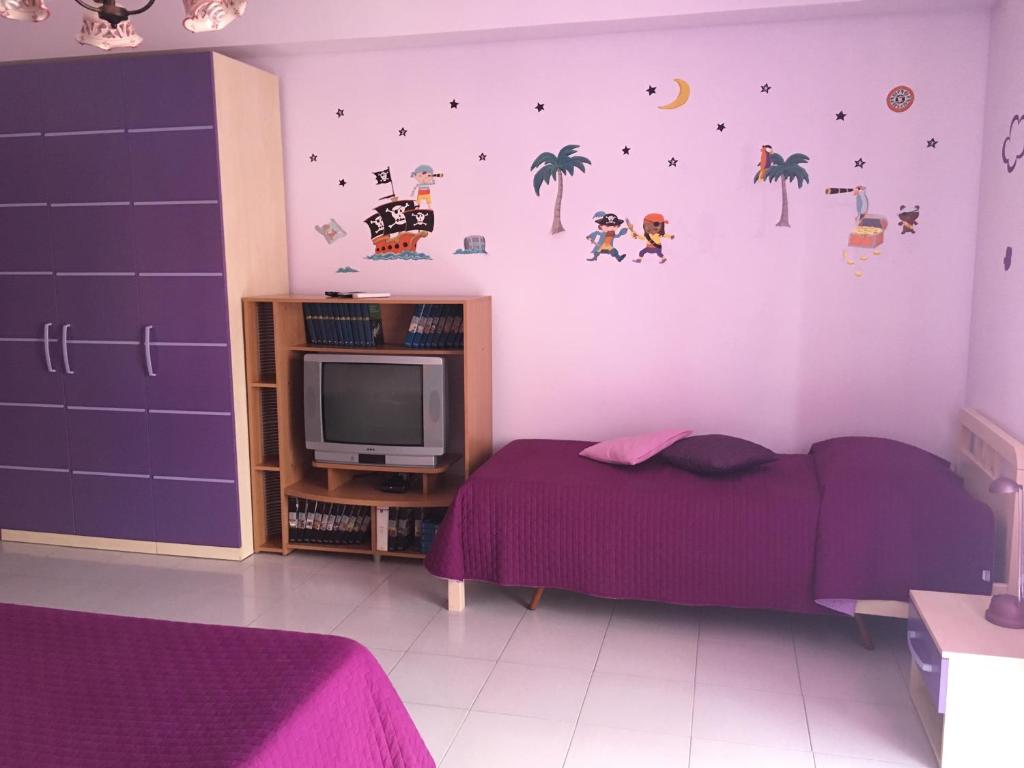 a bedroom with a purple bed and a tv at I Colori dell'Arcobaleno in Santo Stefano di Camastra