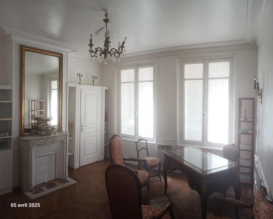 une salle à manger avec une table, des chaises et un lustre dans l'établissement Ternes - Parisian appartment, à Paris