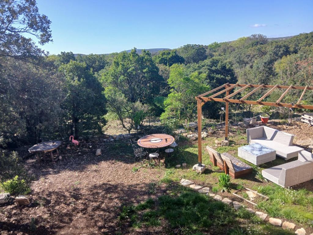 une cour avec une table de pique-nique et une pergola en bois dans l'établissement Face à la garrigue, à Viols-le-Fort