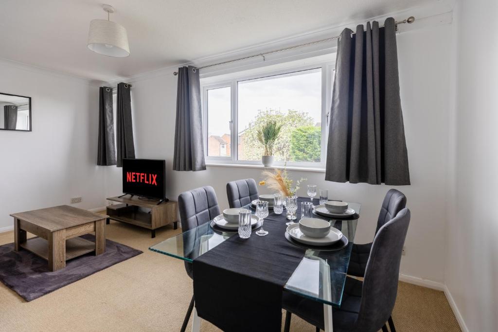 a dining room with a table and chairs and a tv at Stylish Home Near Addenbrookes Hospital by Traboule Properties Ltd in Shelford