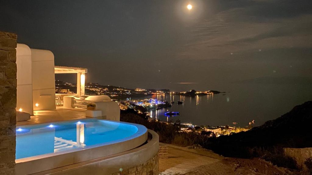 a pool in a house with a view of the water at night at Villa Camelia 2 - Psarou View - Private pool and Jacuzzi in Mýkonos City